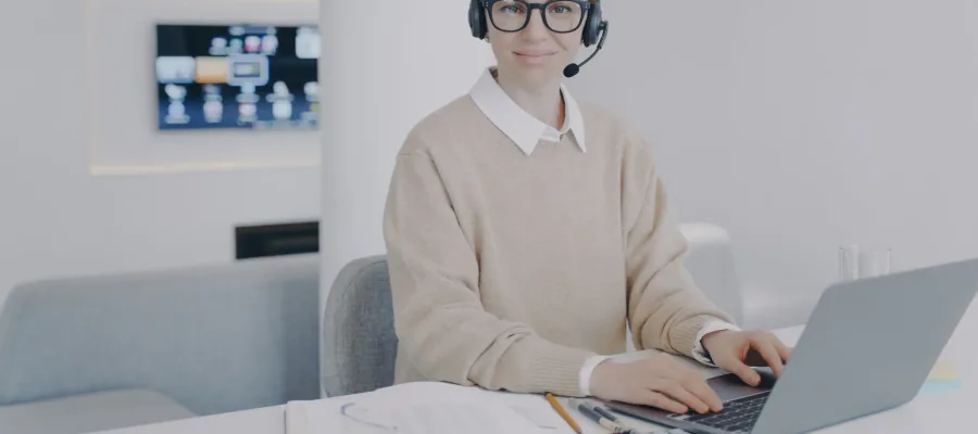 System administrator at workplace in office. Young woman is consultant of call center. European friendly girl in headset is talking to client. Customer support concept.